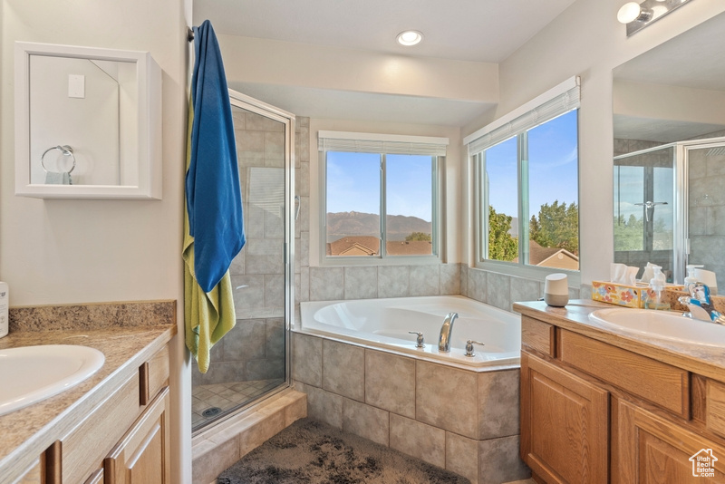 Bathroom with two vanities, a shower stall, and a garden tub