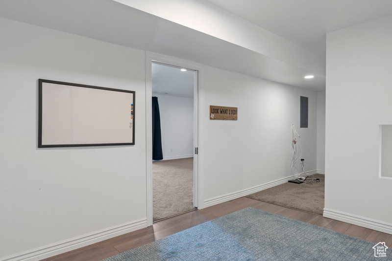 Unfurnished room with wood finished floors, baseboards, and electric panel