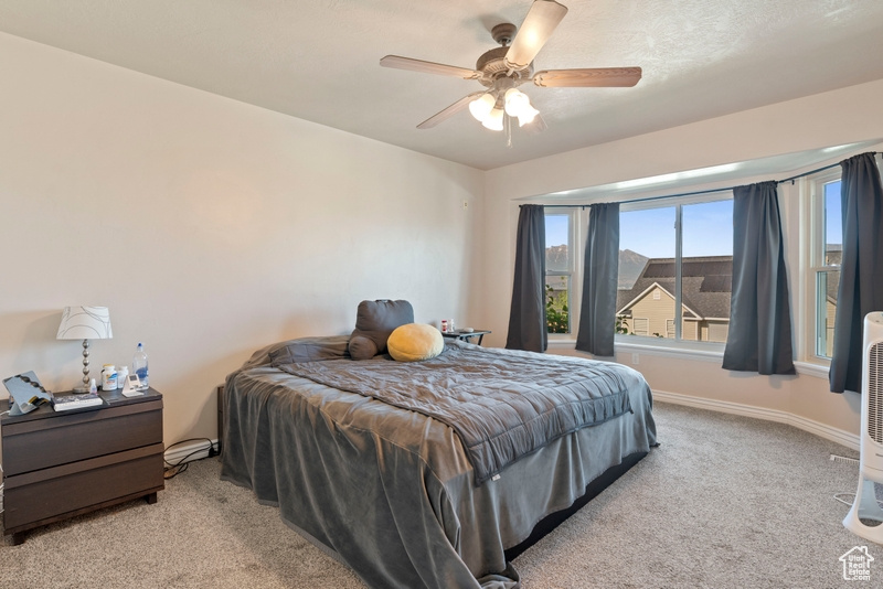 Carpeted bedroom featuring a ceiling fan and baseboards