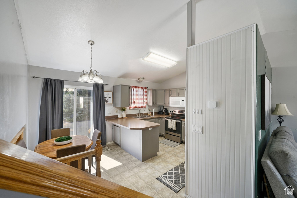 Kitchen featuring stainless steel electric range, white microwave, a sink, a peninsula, and gray cabinets