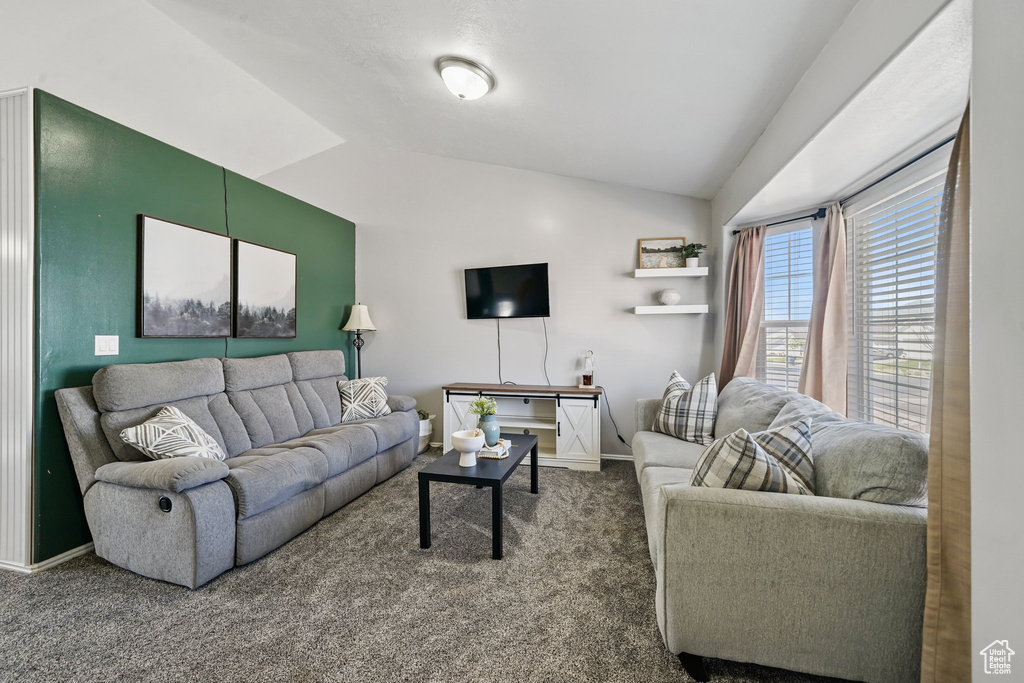Living room with vaulted ceiling, carpet flooring, and baseboards