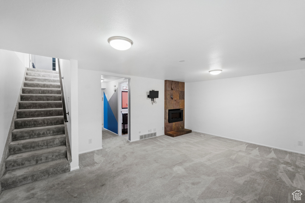 Finished below grade area with stairway, carpet floors, a fireplace, and baseboards