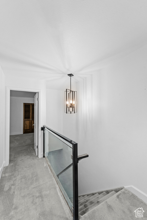 Staircase featuring carpet floors, baseboards, and a chandelier
