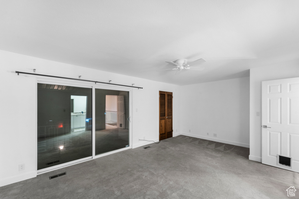 Carpeted empty room with baseboards and a ceiling fan