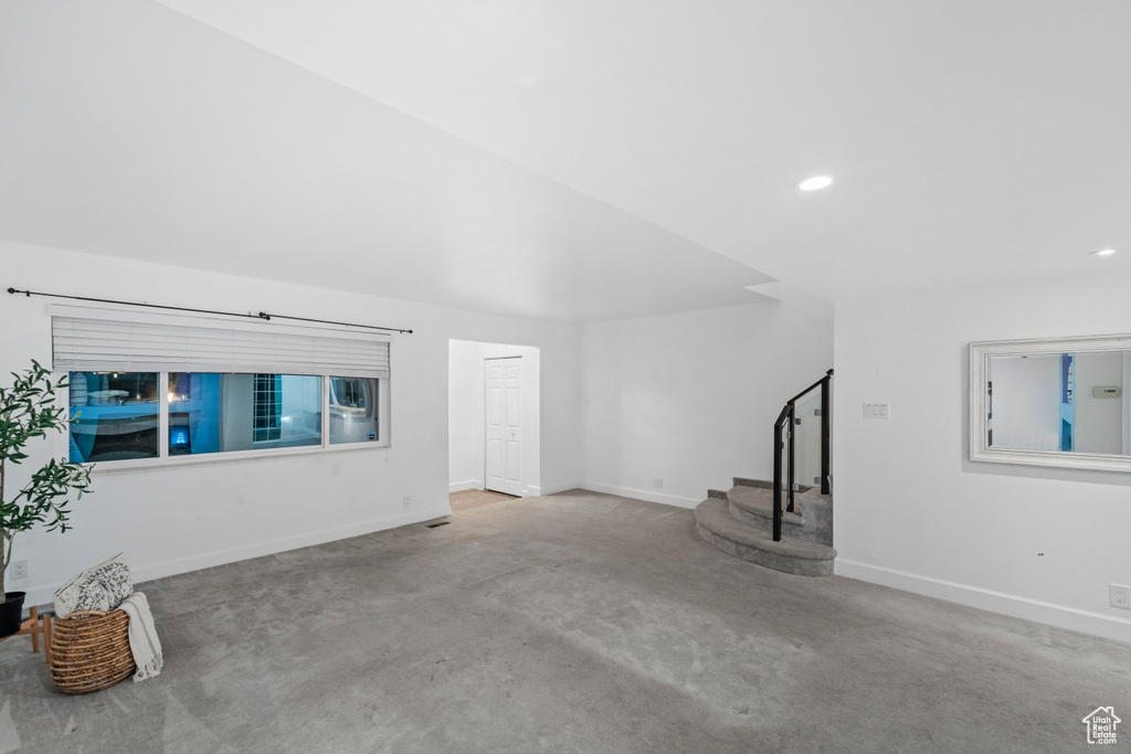 Unfurnished living room with stairs, carpet floors, baseboards, and recessed lighting