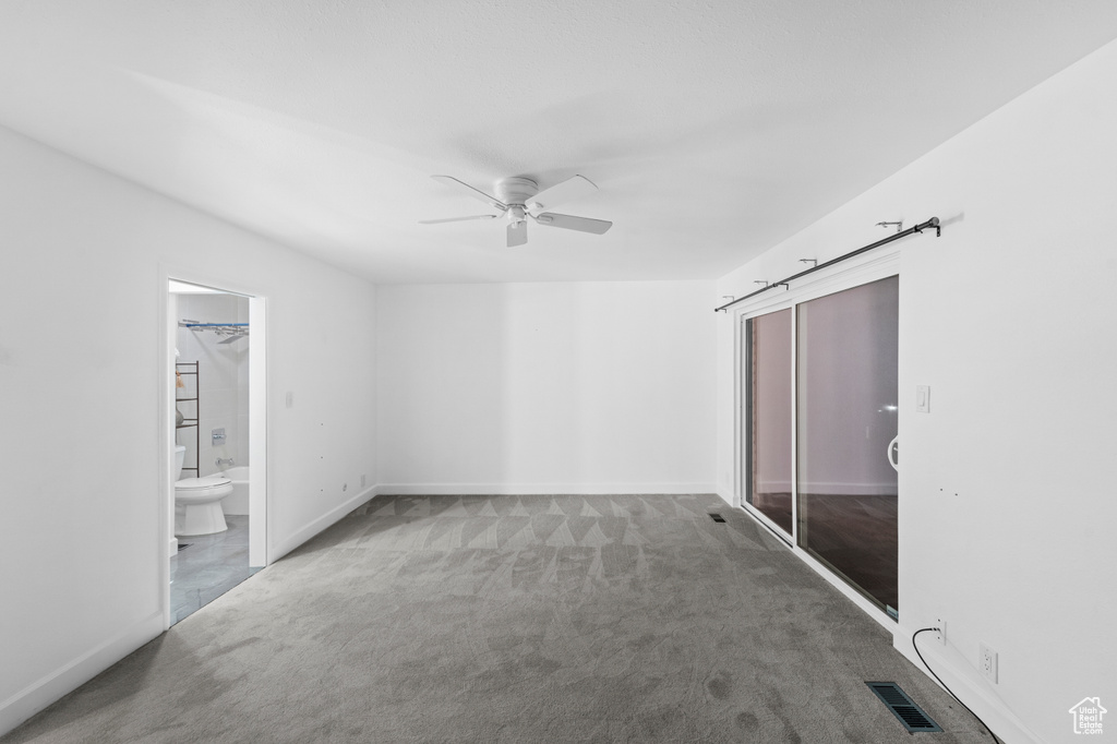 Carpeted spare room featuring a ceiling fan and baseboards