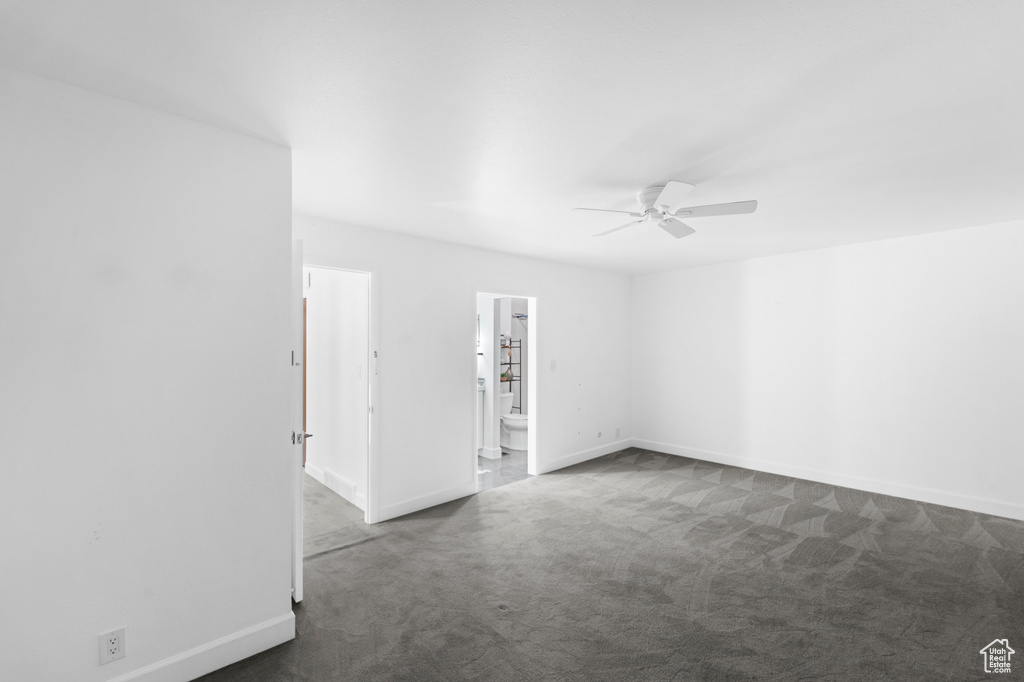 Spare room with dark carpet, a ceiling fan, and baseboards