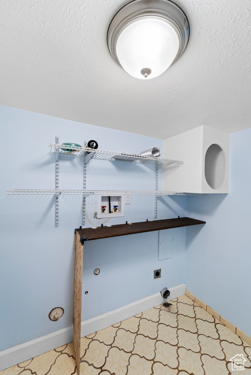 Laundry room featuring hookup for a washing machine, hookup for an electric dryer, a textured ceiling, and baseboards