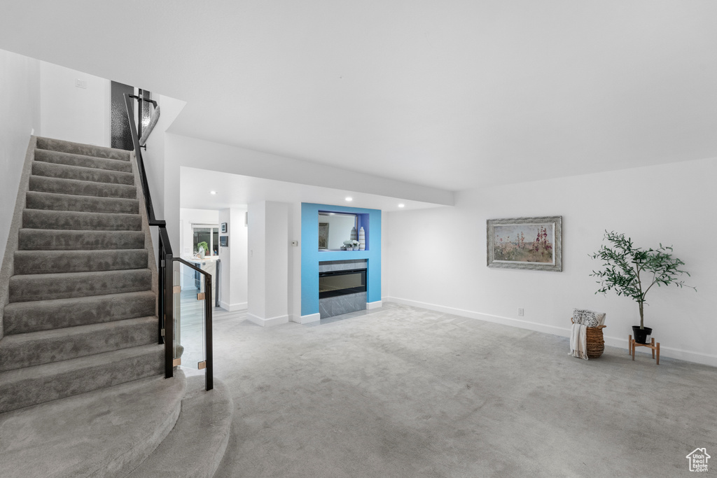 Unfurnished living room with light colored carpet, stairs, recessed lighting, and baseboards