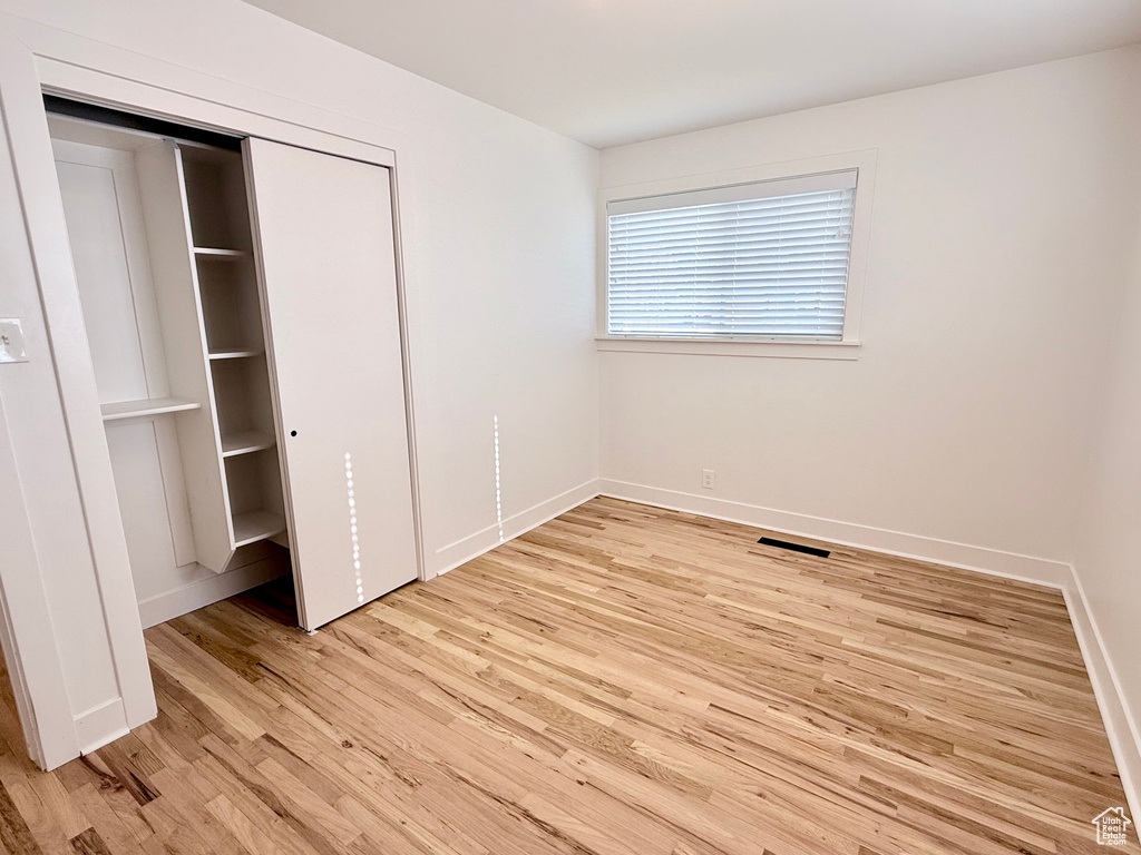 Unfurnished bedroom with light wood-type flooring, baseboards, and a closet