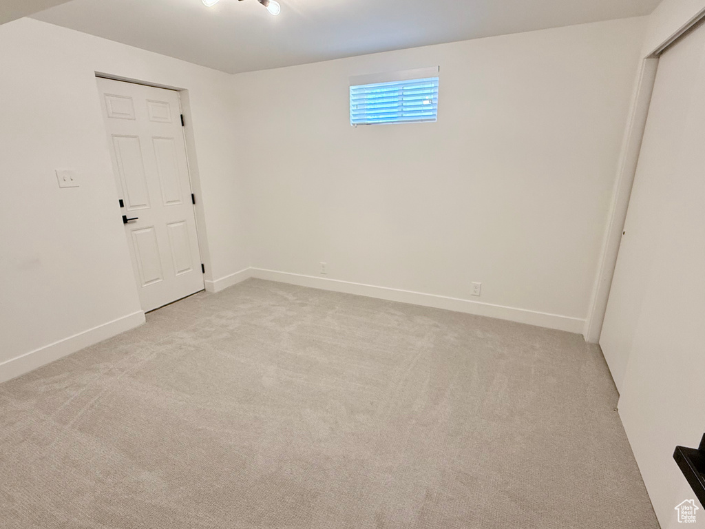 Unfurnished room featuring light carpet and baseboards