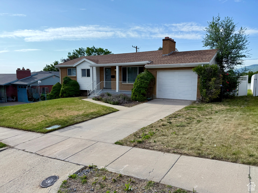 Ranch-style home featuring covered porch, an attached garage, driveway, brick siding, and a chimney