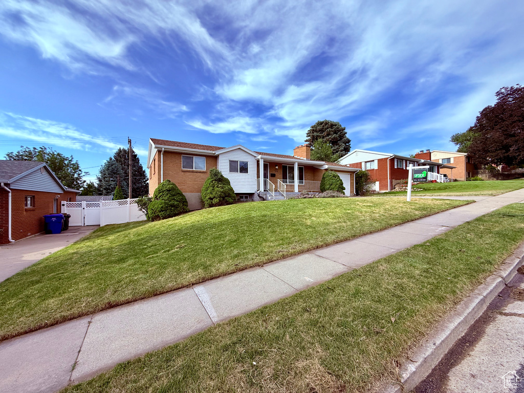 Single story home featuring a chimney, a porch, brick siding, and concrete driveway