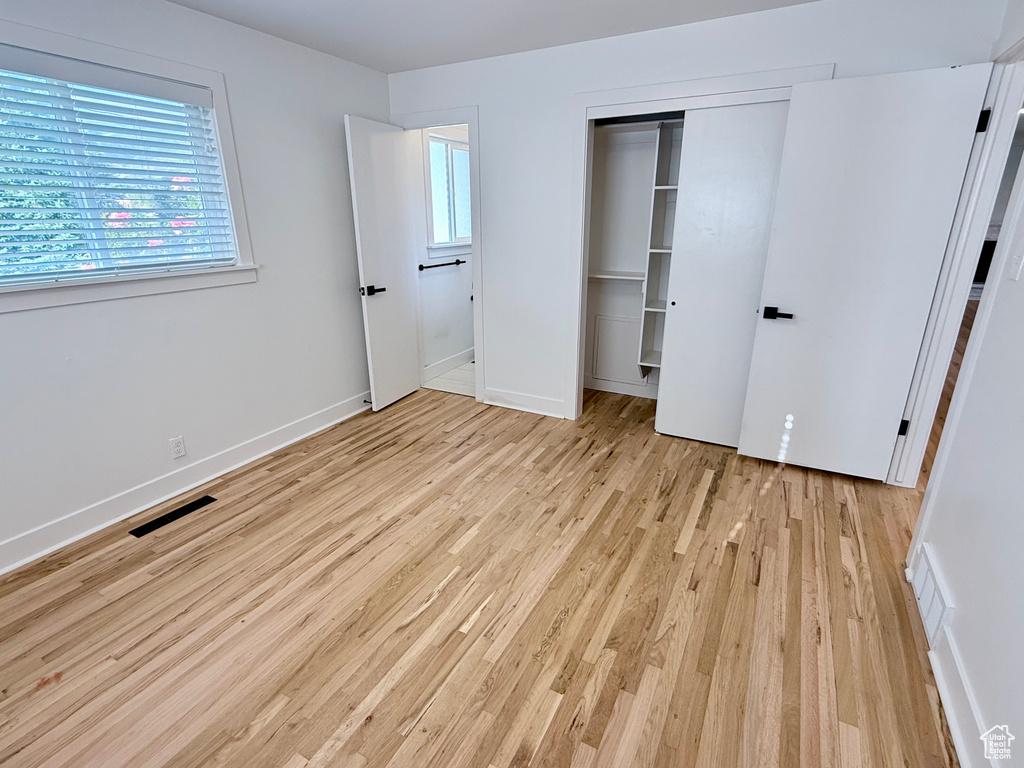 Unfurnished bedroom with light wood finished floors, a closet, multiple windows, and baseboards
