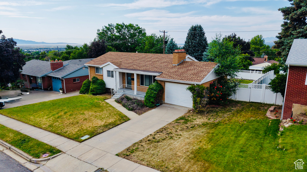 View of front facade featuring driveway, a garage, a chimney, and brick siding
