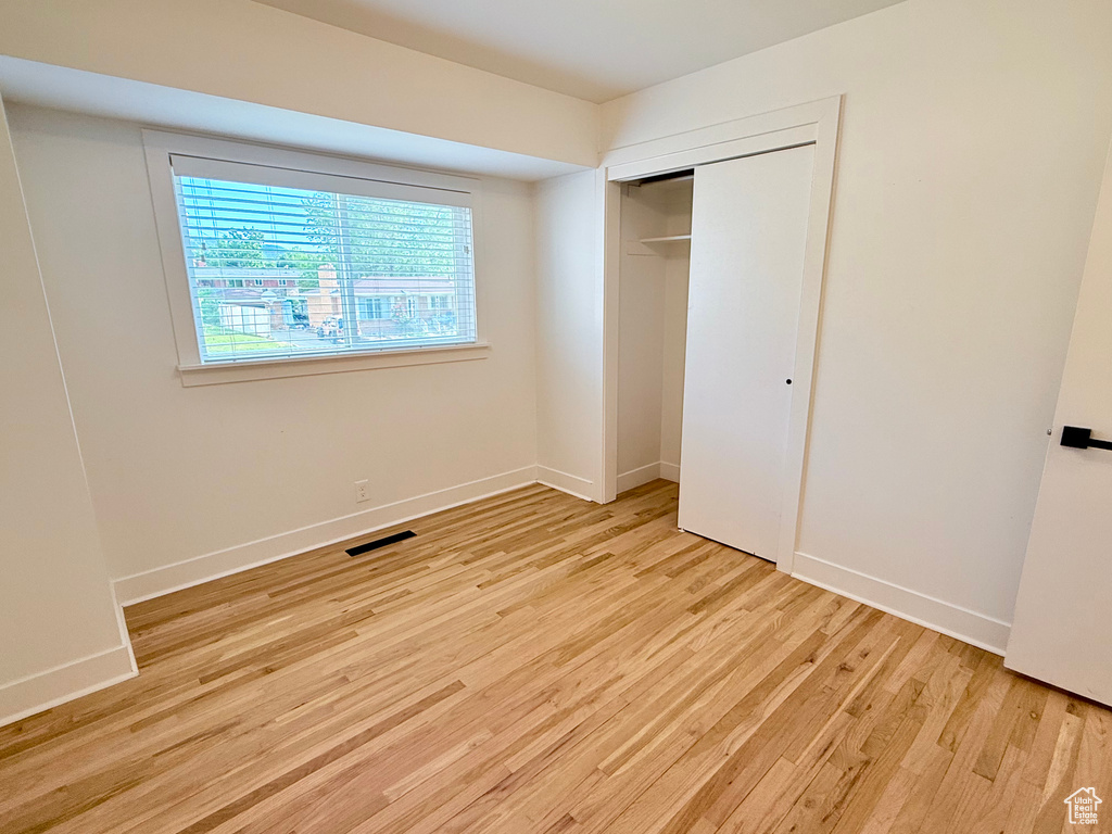 Unfurnished bedroom featuring light wood finished floors, a closet, and baseboards