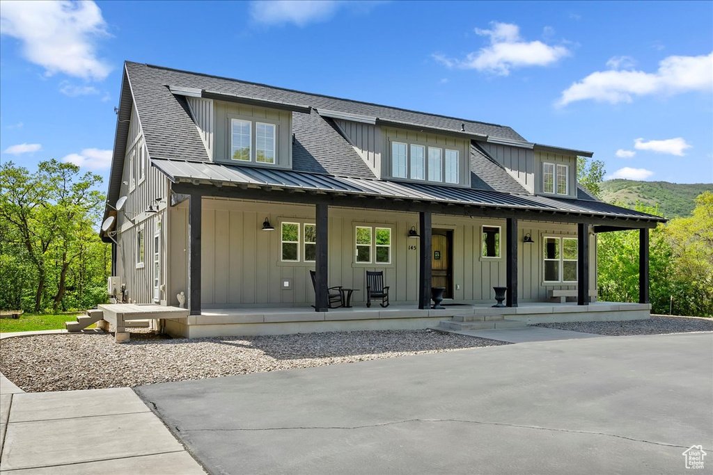 View of front of house featuring board and batten siding, a porch, metal roof, and a standing seam roof