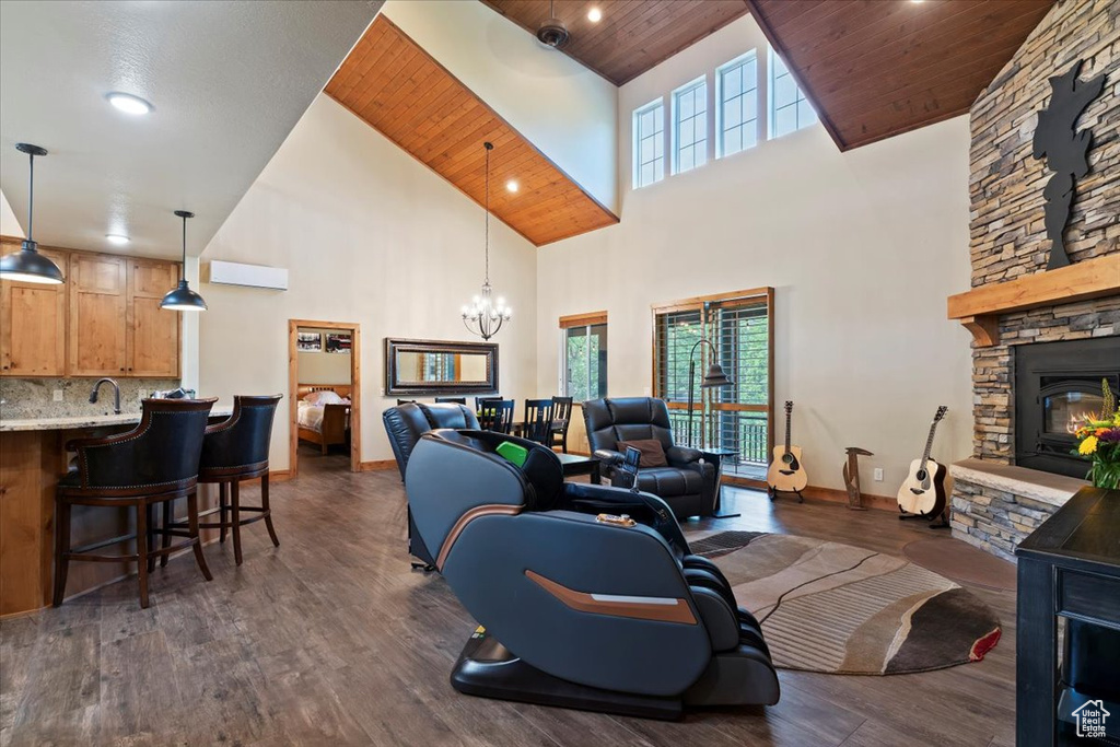 Living room featuring high vaulted ceiling, healthy amount of natural light, a chandelier, wood ceiling, and a stone fireplace