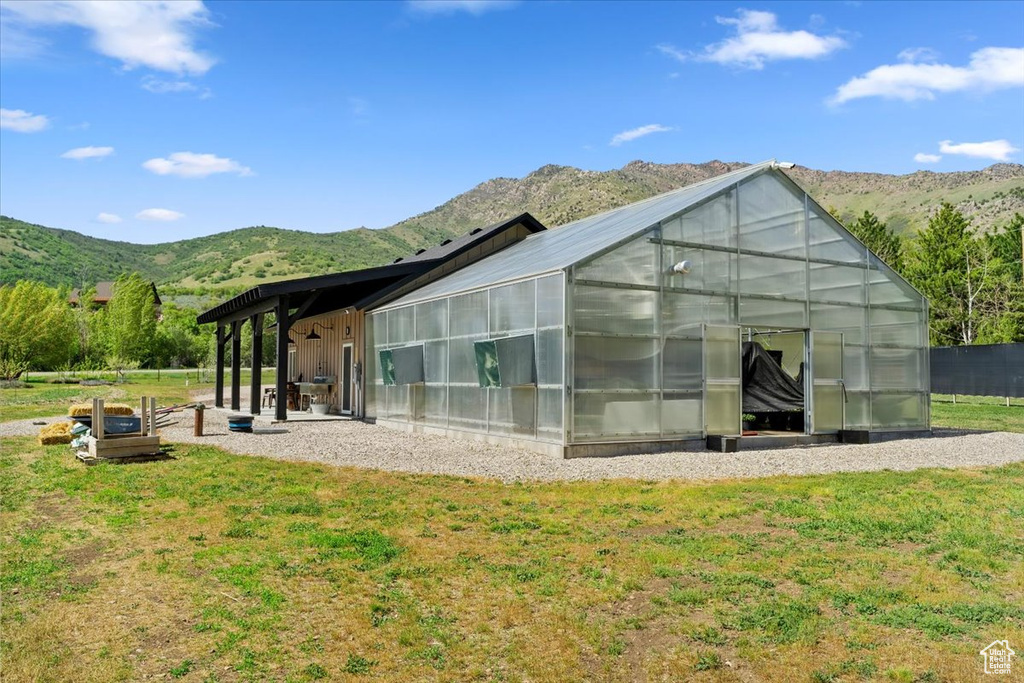 Rear view of house featuring an exterior structure, a mountain view, and an outbuilding