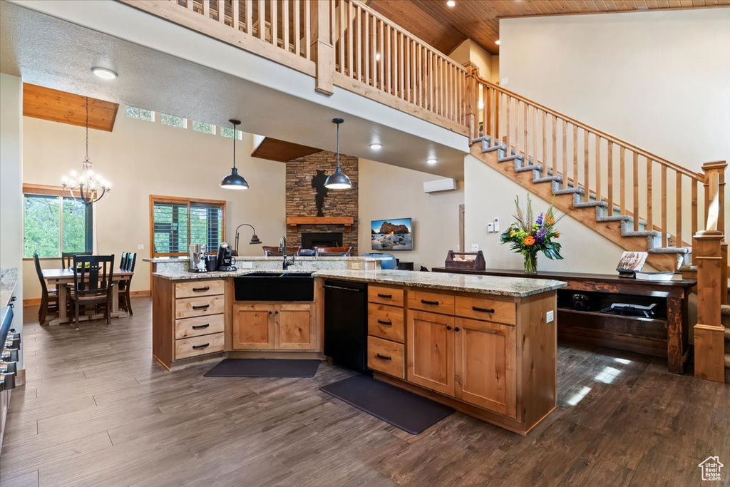 Kitchen featuring high vaulted ceiling, black dishwasher, a sink, dark wood-style floors, and a fireplace
