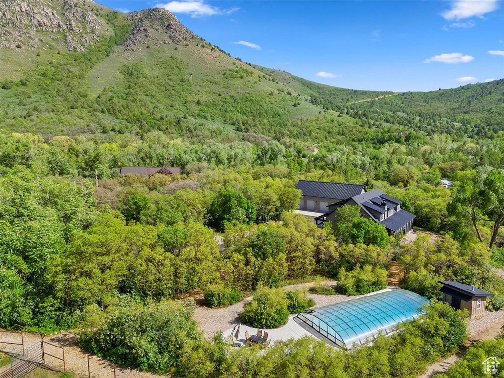 Aerial view of property and surrounding area featuring a heavily wooded area and a mountain backdrop