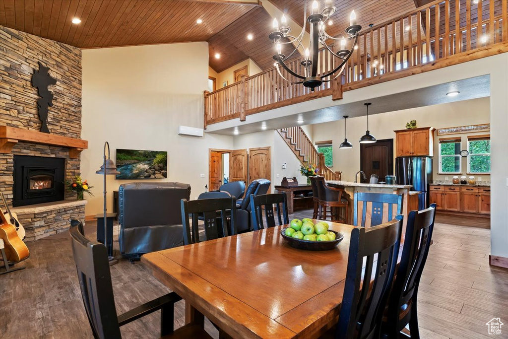 Dining area featuring wood finished floors, high vaulted ceiling, wooden ceiling, stairs, and a chandelier