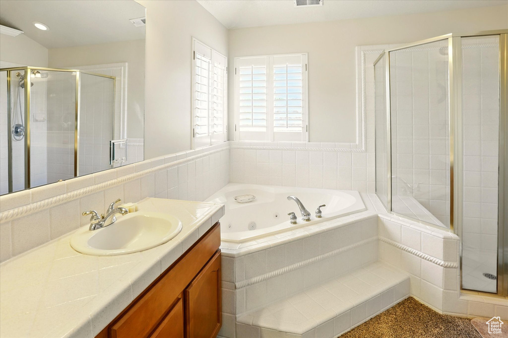 Bathroom featuring vanity, a shower stall, and a whirlpool tub