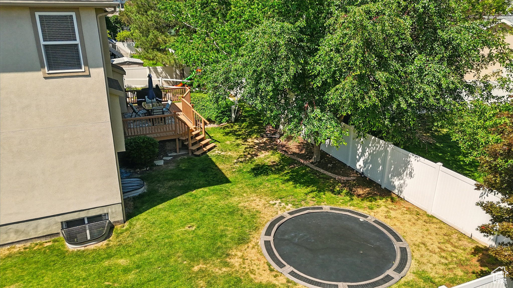 View of yard with a trampoline, a wooden deck, and stairway