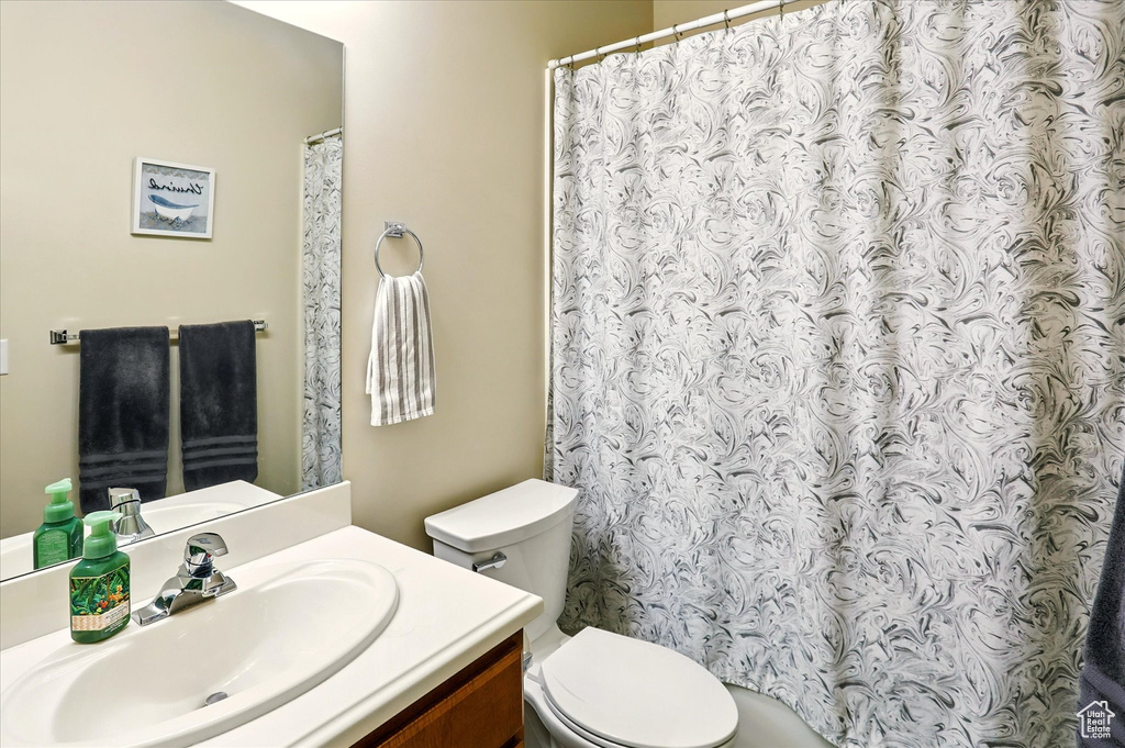 Bathroom with toilet, vanity, and a shower with curtain