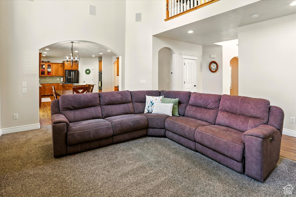 Living area with a towering ceiling, arched walkways, recessed lighting, a chandelier, and baseboards