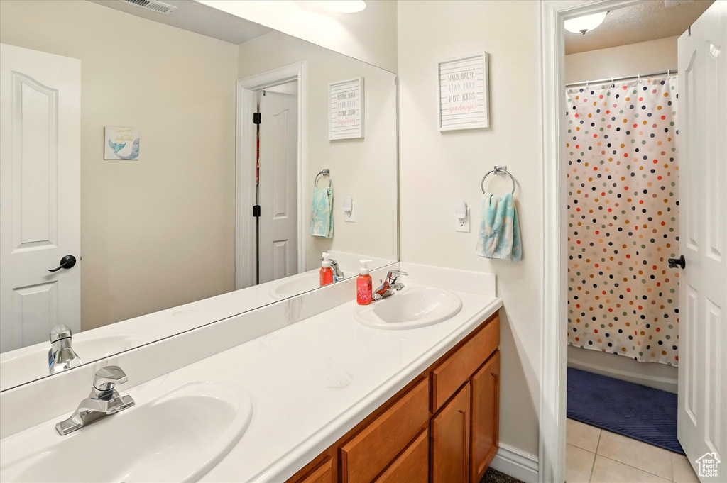 Bathroom with double vanity, tile patterned flooring, and a shower with curtain