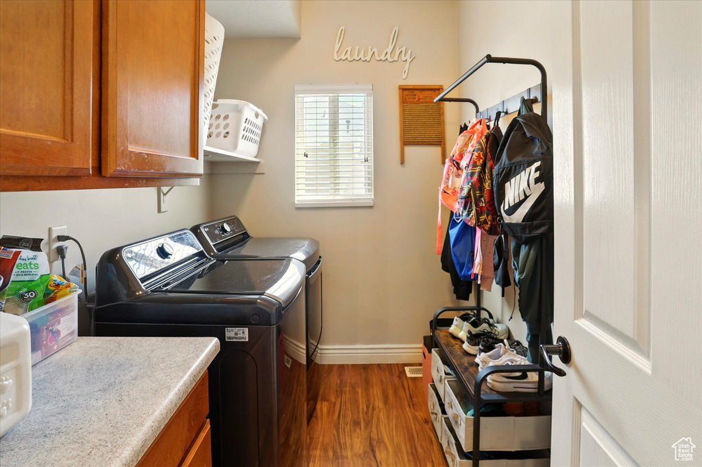 Laundry room featuring cabinet space, washer and clothes dryer, dark wood-style floors, and baseboards