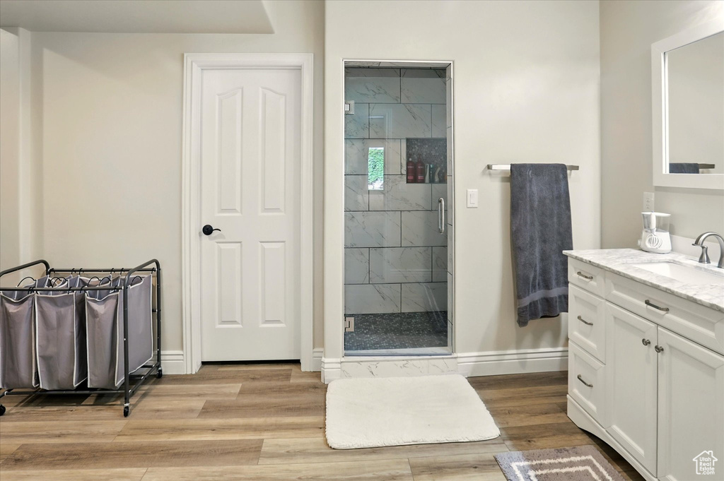 Full bathroom featuring vanity, a stall shower, baseboards, and wood finished floors