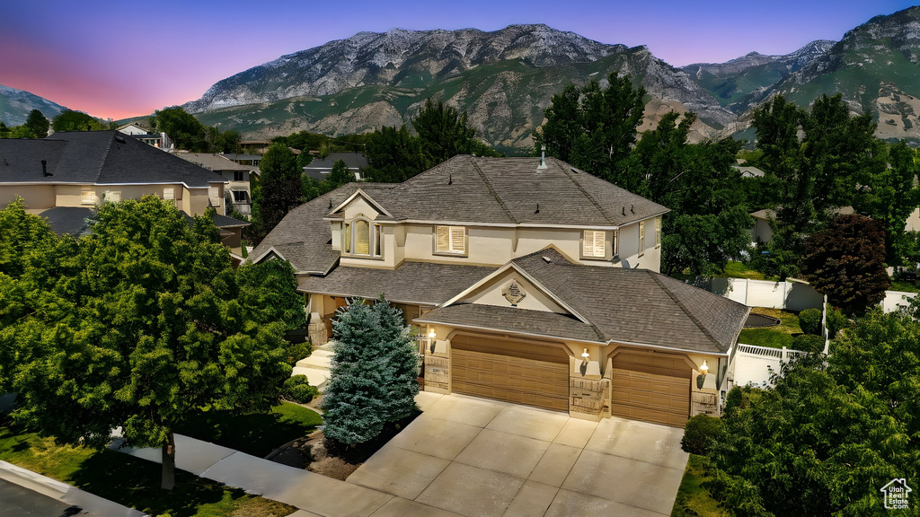 View of front facade featuring stucco siding, driveway, a mountain view, and a garage