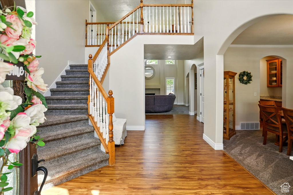 Entrance foyer featuring wood finished floors, ornamental molding, stairs, arched walkways, and baseboards
