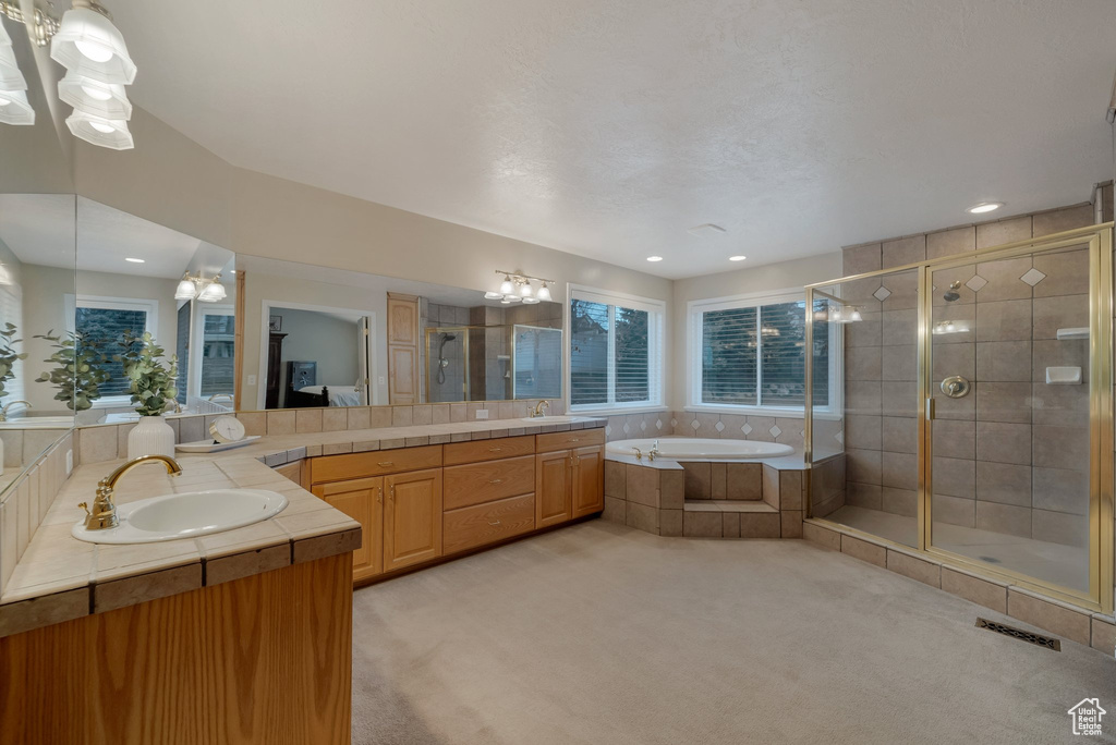 Full bathroom with a stall shower, two vanities, a garden tub, healthy amount of natural light, and recessed lighting