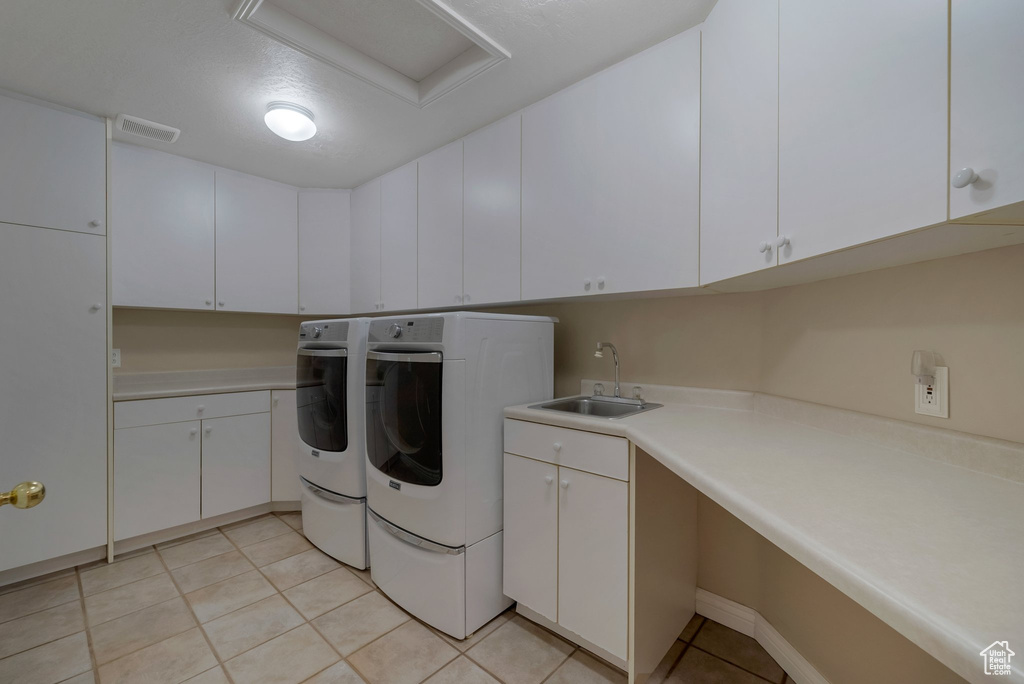 Laundry room featuring separate washer and dryer, cabinet space, and light tile patterned flooring