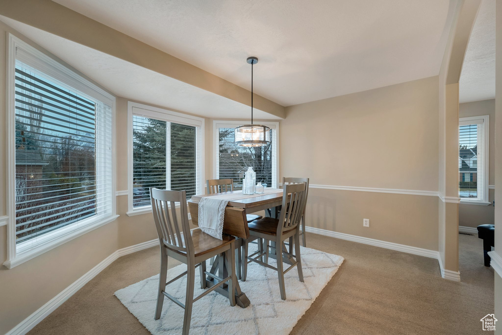 Carpeted dining area with baseboards and a chandelier