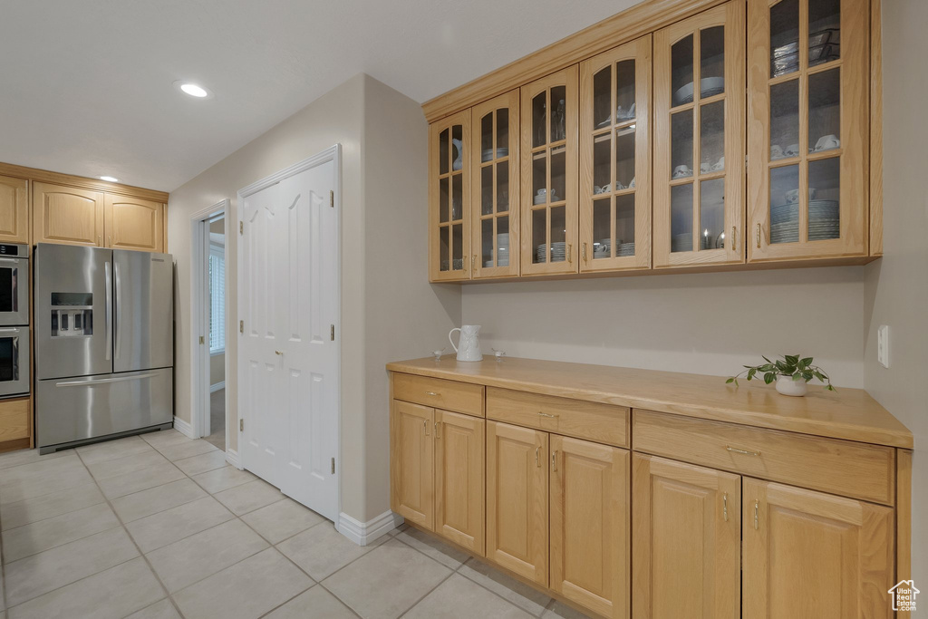 Kitchen featuring appliances with stainless steel finishes, light tile patterned flooring, glass insert cabinets, light countertops, and recessed lighting