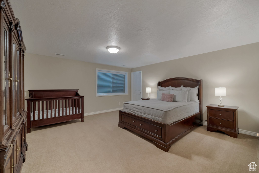 Bedroom with light colored carpet, baseboards, and a textured ceiling