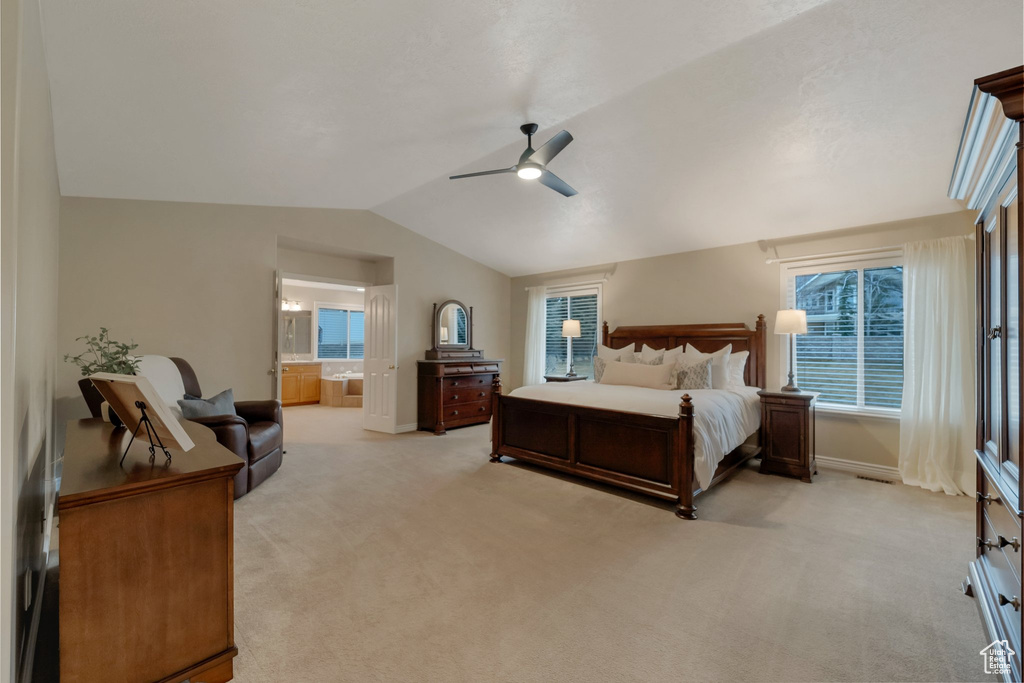 Bedroom with baseboards, vaulted ceiling, light carpet, ensuite bathroom, and a ceiling fan