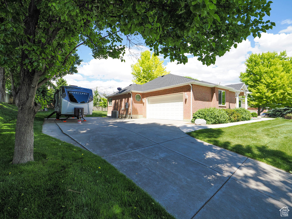 View of side of home featuring a yard, brick siding, an attached garage, and driveway