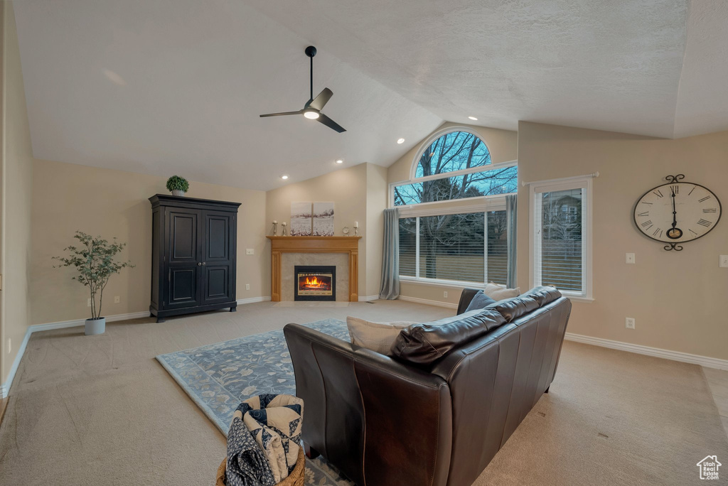 Living room featuring light colored carpet, a ceiling fan, vaulted ceiling, a fireplace, and baseboards