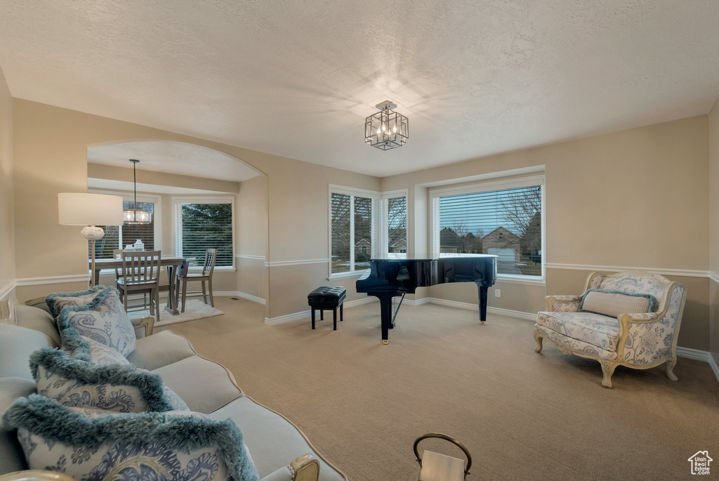 Living room with a chandelier, carpet, healthy amount of natural light, and a textured ceiling