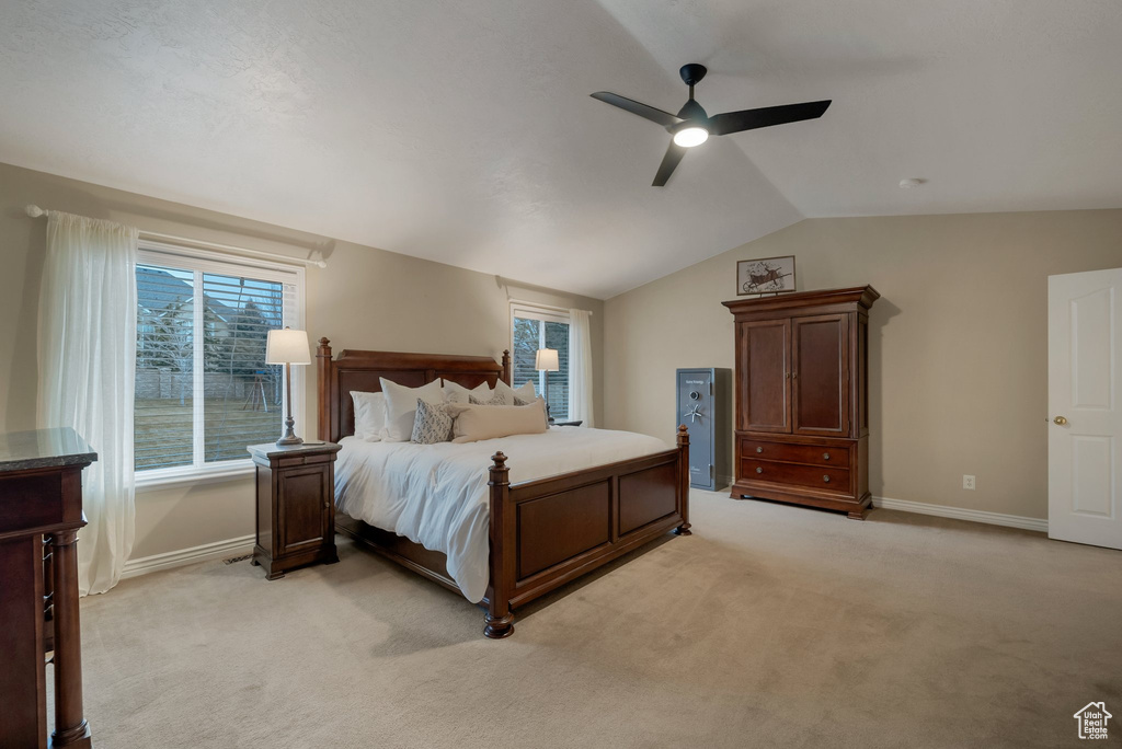 Bedroom with vaulted ceiling, light carpet, baseboards, and ceiling fan
