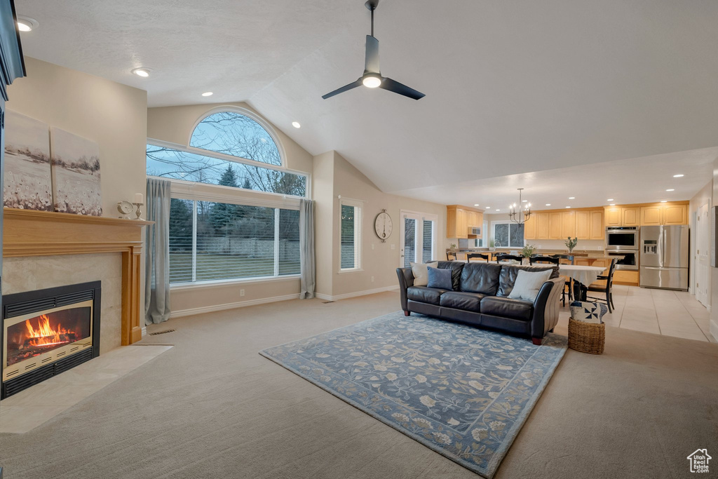 Living area with light carpet, vaulted ceiling, a premium fireplace, a chandelier, and a ceiling fan