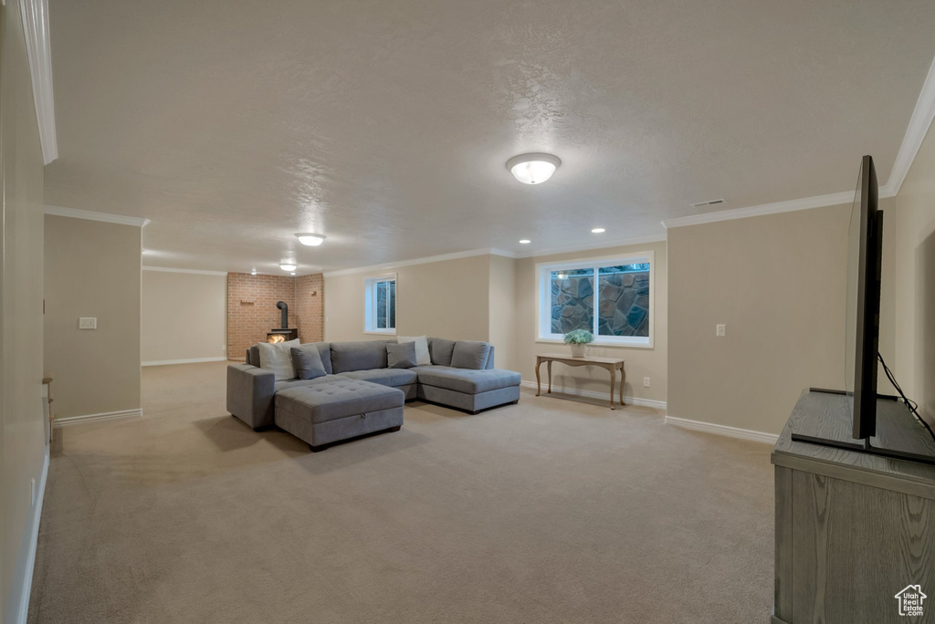 Living area featuring baseboards, light colored carpet, crown molding, and a wood stove