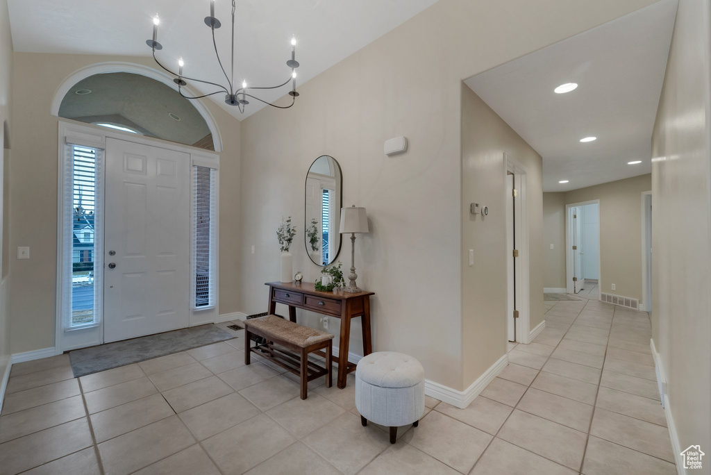 Foyer entrance with light tile patterned floors, baseboards, recessed lighting, a chandelier, and lofted ceiling
