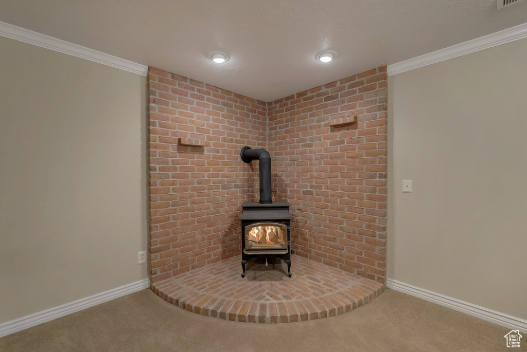 Detailed view of a wood stove, carpet, baseboards, and crown molding