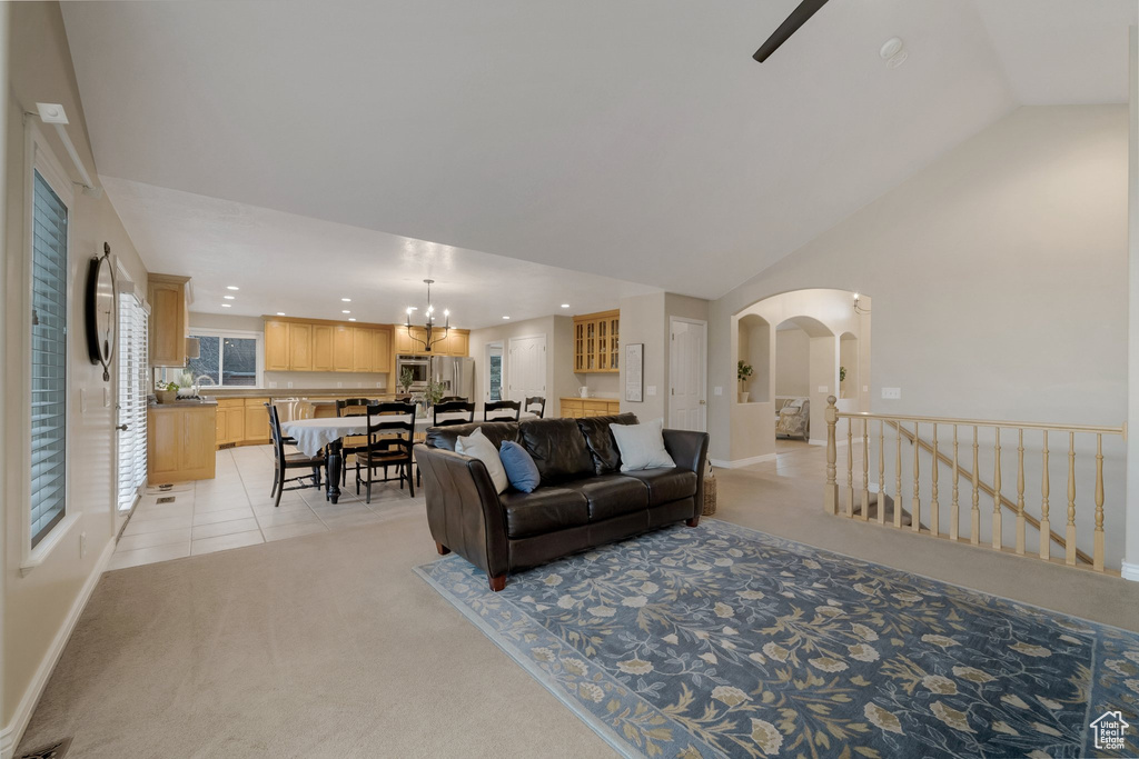 Living area featuring light colored carpet, recessed lighting, arched walkways, vaulted ceiling, and a chandelier
